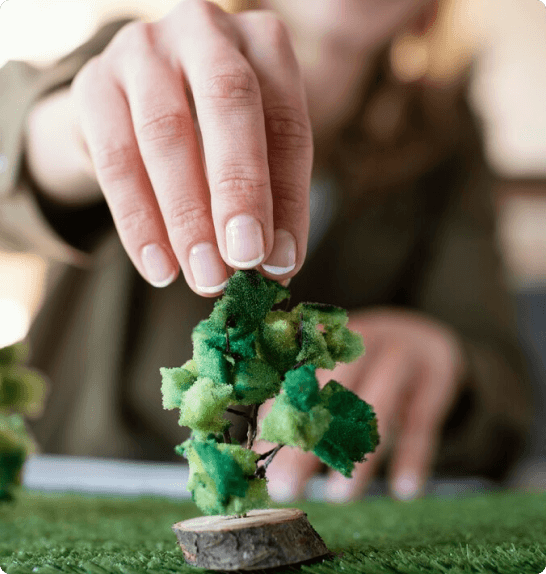 Person placing miniature tree model