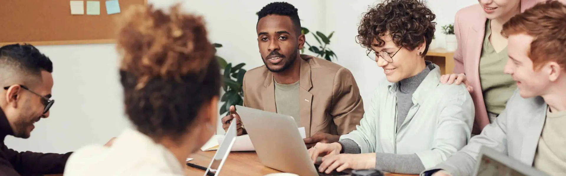Diverse team collaborating around a laptop discussing whether to build a dedicated sustainability function